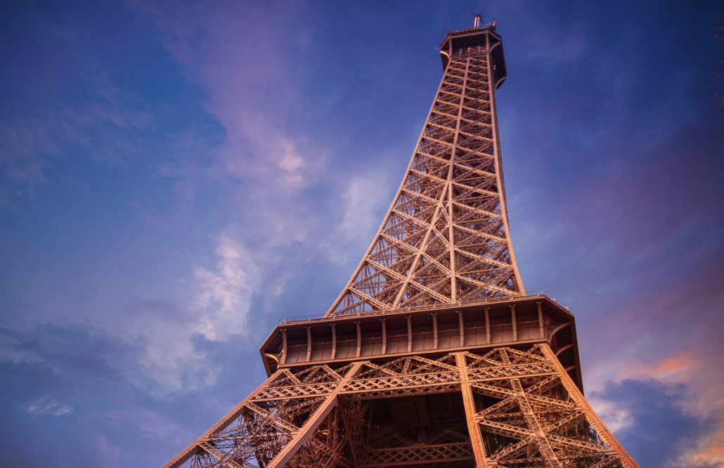 photo of the eiffel tower shot from below towards the top in a colourful sky